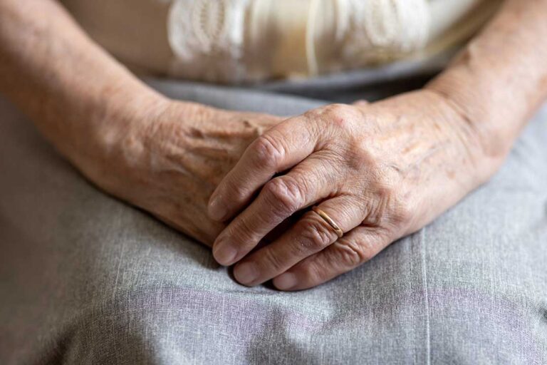 Older adult and family member organize labeled clothing and photographs for a move into assisted living.